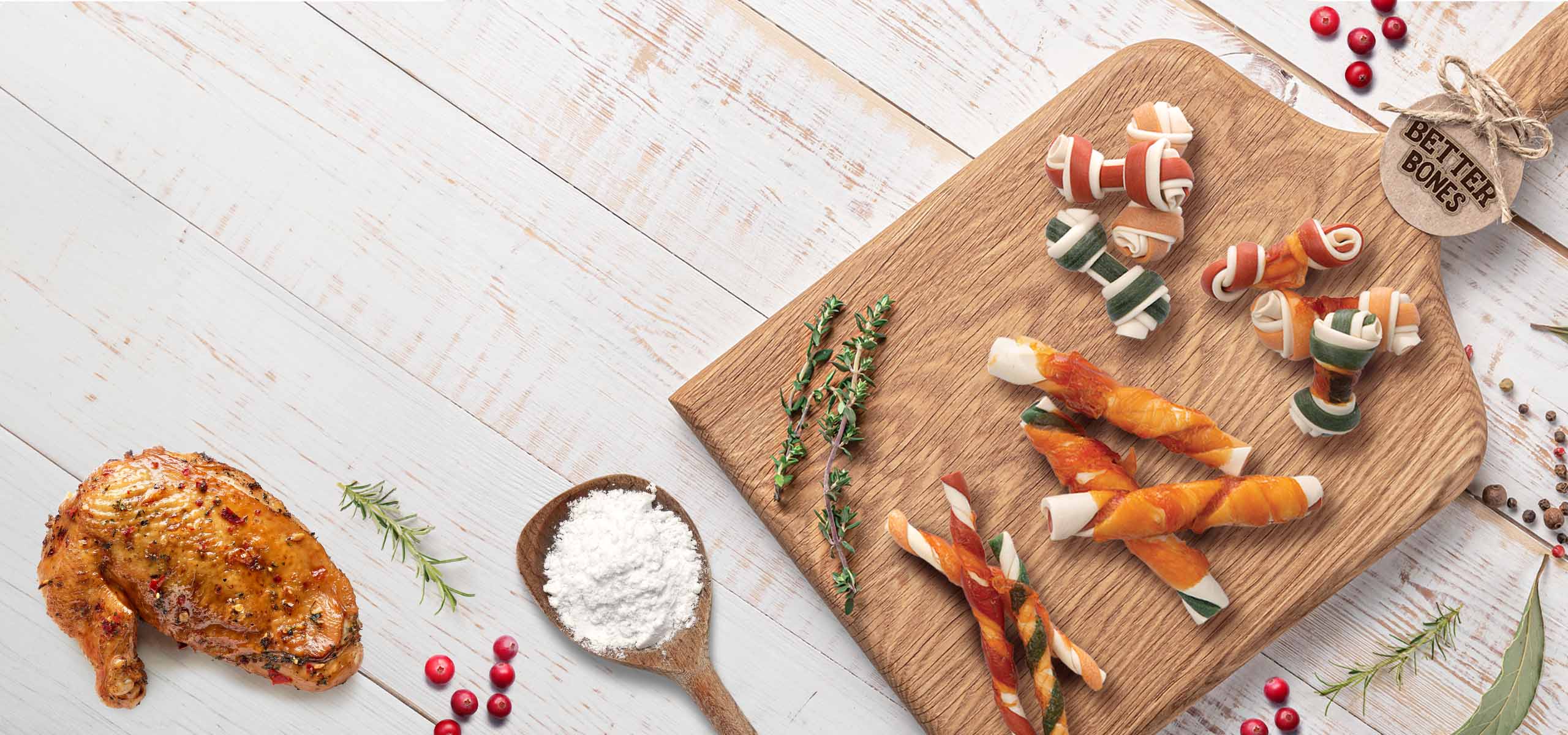 All different types of Zoë Better Bones laying on a wooden board, surrounded with their natural ingredients